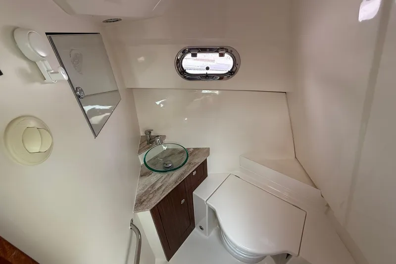  Yacht Photos Pics 2017 Pursuit OS 325 Offshore boat bathroom with sink, toilet, and porthole window.