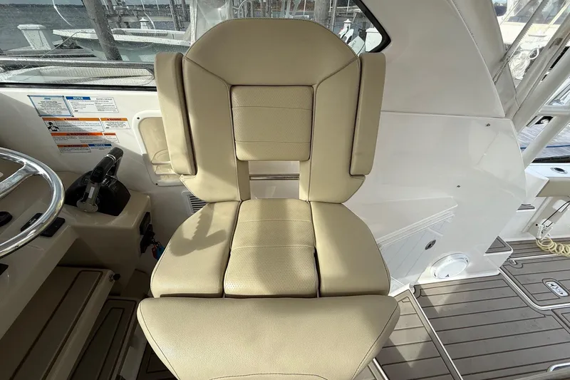 Yacht Photos Pics Captain's chair on 2017 Pursuit OS 325 Offshore boat, featuring beige upholstery and helm controls.