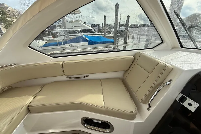  Yacht Photos Pics Interior view of 2017 Pursuit OS 325 Offshore boat with beige seating and marina backdrop.