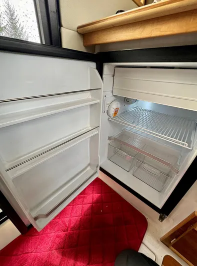  Yacht Photos Pics Open refrigerator inside 2022 Cutwater C32 Northwest Edition boat, with red mat on floor.