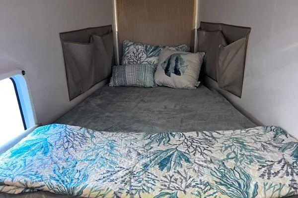 Meraki Yacht Photos Pics Cozy bed in NEEL 43, 2022 model, with patterned bedding and wall storage pockets.