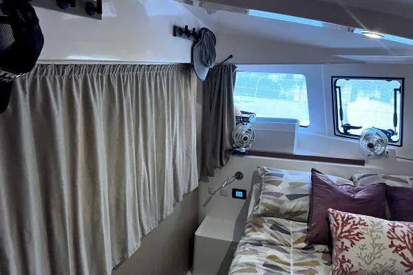 Meraki Yacht Photos Pics Interior of 2022 NEEL 43 boat with cozy bed, curtains, and windows.