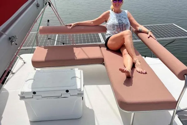 Meraki Yacht Photos Pics Woman relaxing on NEEL 43 trimaran deck, 2022 model, with solar panels and cooler.