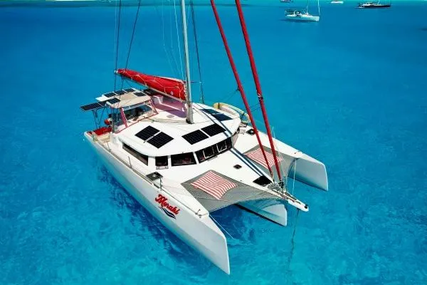 Meraki Yacht Photos Pics 2022 NEEL 43 trimaran sailing on clear blue water, featuring solar panels and red sails.