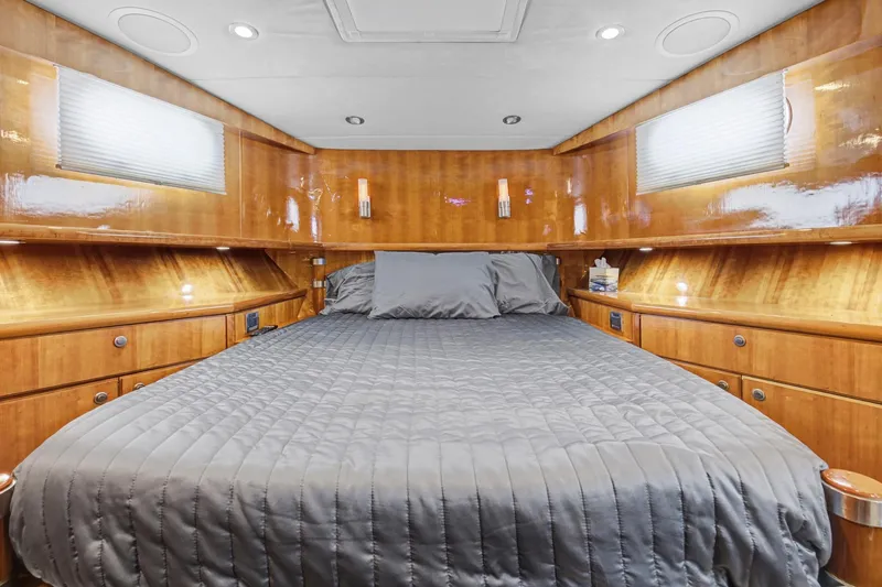  Yacht Photos Pics Luxurious bedroom interior of 2004 Queenship 76 Baretta yacht with wood paneling and cozy bedding.