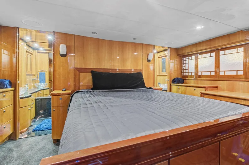  Yacht Photos Pics Luxurious bedroom interior of 2004 Queenship 76 Baretta yacht with wood paneling and modern amenities.