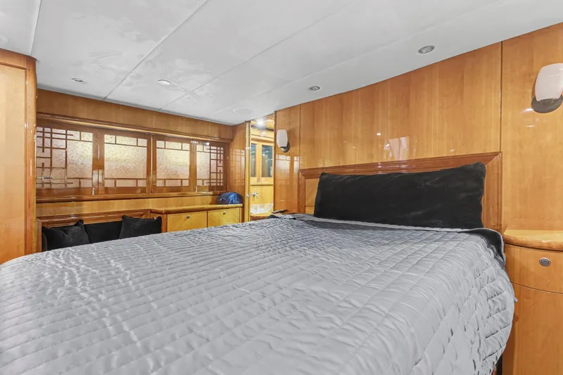  Yacht Photos Pics Luxurious bedroom interior of 2004 Queenship 76 Baretta yacht with wood paneling and modern design.