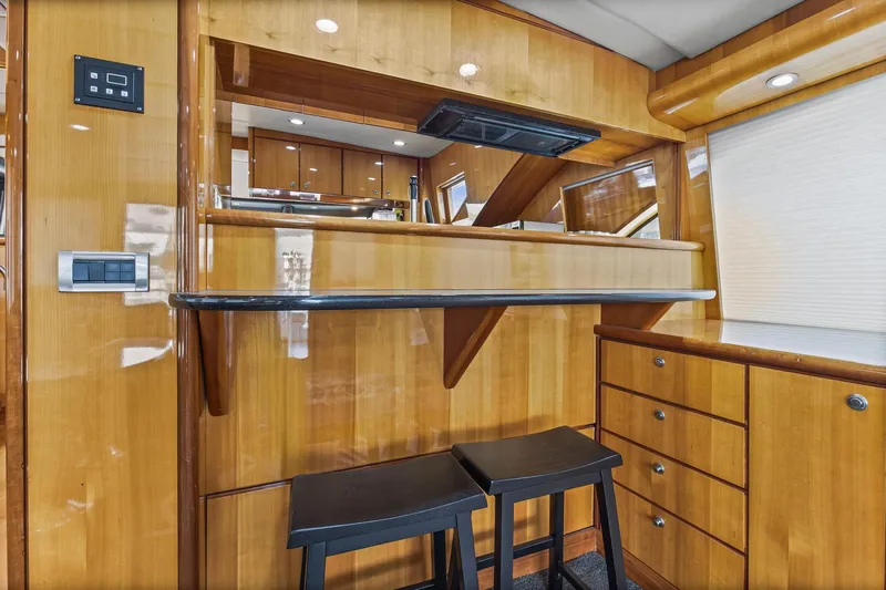  Yacht Photos Pics Luxurious 2004 Queenship 76 Baretta yacht interior with wooden cabinetry and bar stools.