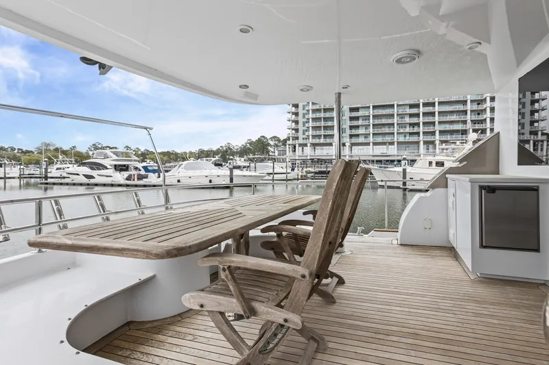  Yacht Photos Pics Luxury yacht deck with wooden table and chairs, overlooking marina. Queenship 76 Baretta, 2004 model.