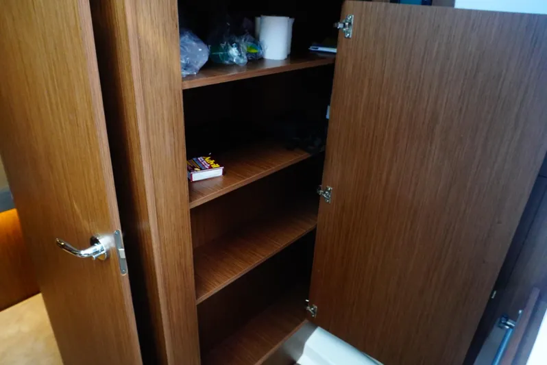 Boondoggle Yacht Photos Pics Open wooden cabinet with shelves inside a 2022 Beneteau Antares 11 boat.