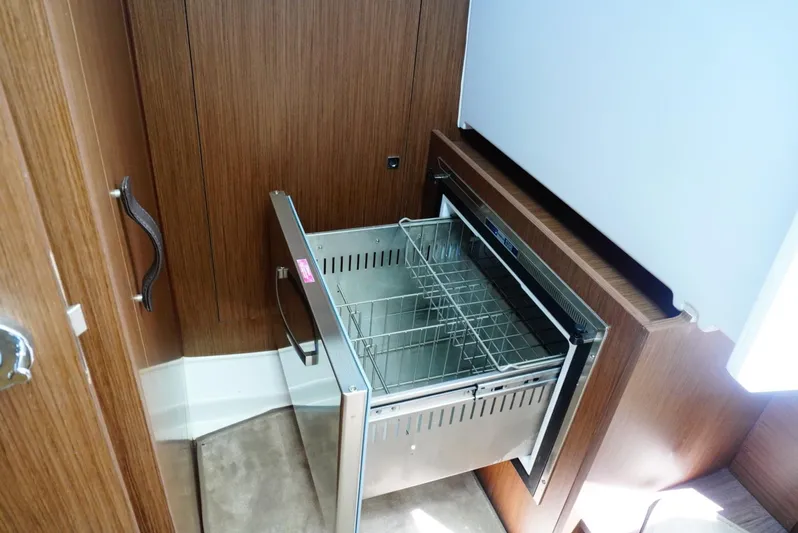 Boondoggle Yacht Photos Pics Built-in drawer refrigerator on 2022 Beneteau Antares 11 yacht, open with wire basket.