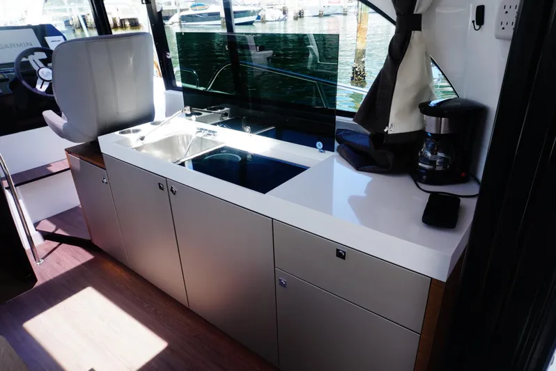 Boondoggle Yacht Photos Pics Modern kitchen area in 2022 Beneteau Antares 11 boat with sleek cabinetry and appliances.