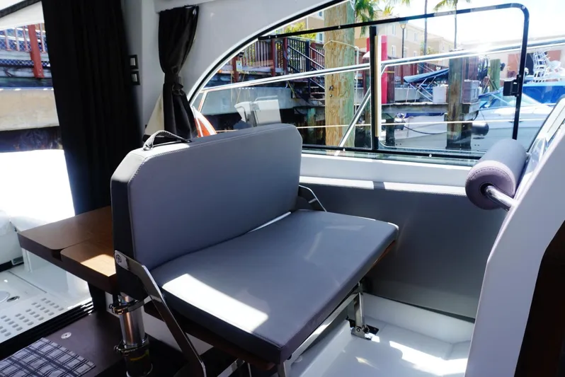 Boondoggle Yacht Photos Pics 2022 Beneteau Antares 11 interior with gray seating and marina view through window.