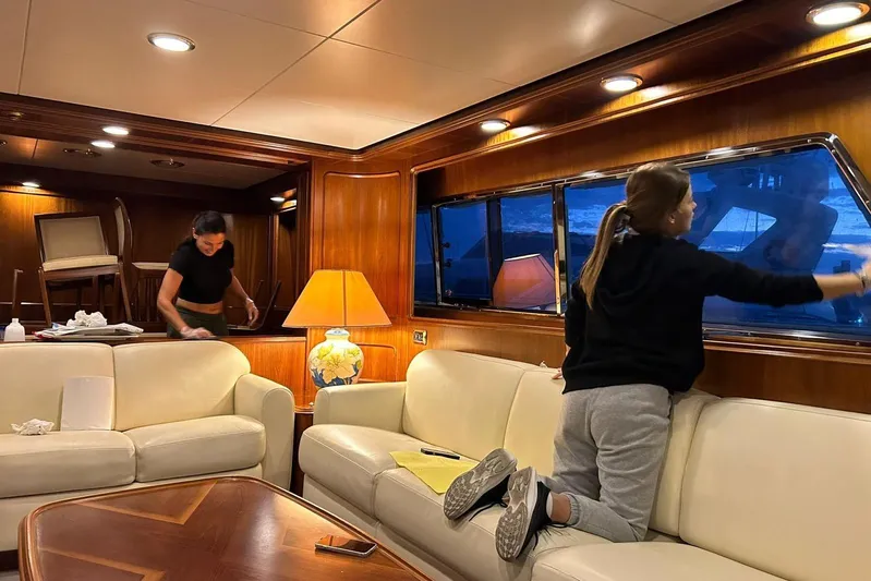  Yacht Photos Pics Interior of 1998 Sanlorenzo 82 yacht with two people cleaning, featuring elegant wood paneling.