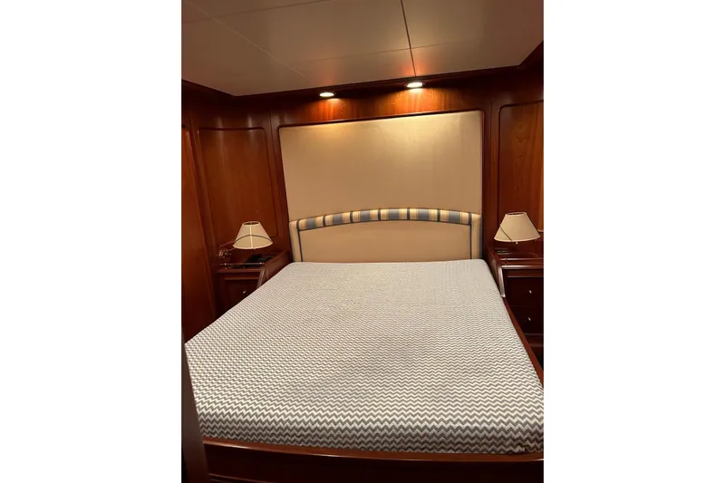  Yacht Photos Pics Luxurious bedroom interior on 1998 Sanlorenzo 82 yacht with elegant wood paneling.