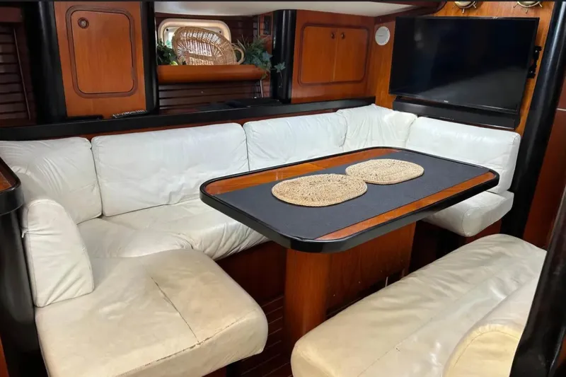 Zephyrus Yacht Photos Pics Interior of 1991 Beneteau Oceanis 50 yacht with white seating and wooden accents.