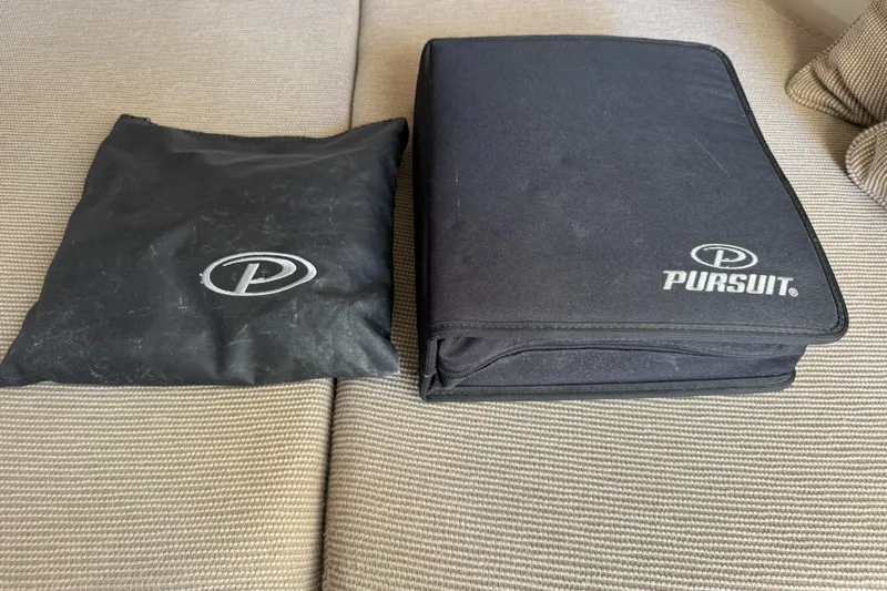  Yacht Photos Pics Black Pursuit LS 345 Drummond Runner 2006 bags on beige fabric surface.