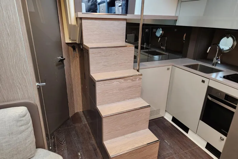  Yacht Photos Pics Modern kitchen interior on 2023 Cranchi M44 HT yacht with wooden stairs and sleek appliances.