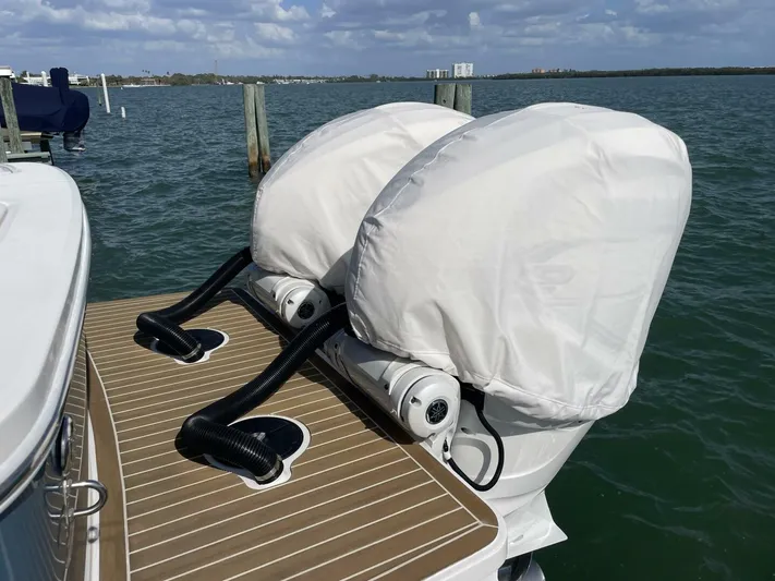 Yacht Photos Pics 2023 Regulator 31 boat with covered outboard motors on a wooden deck by the water.