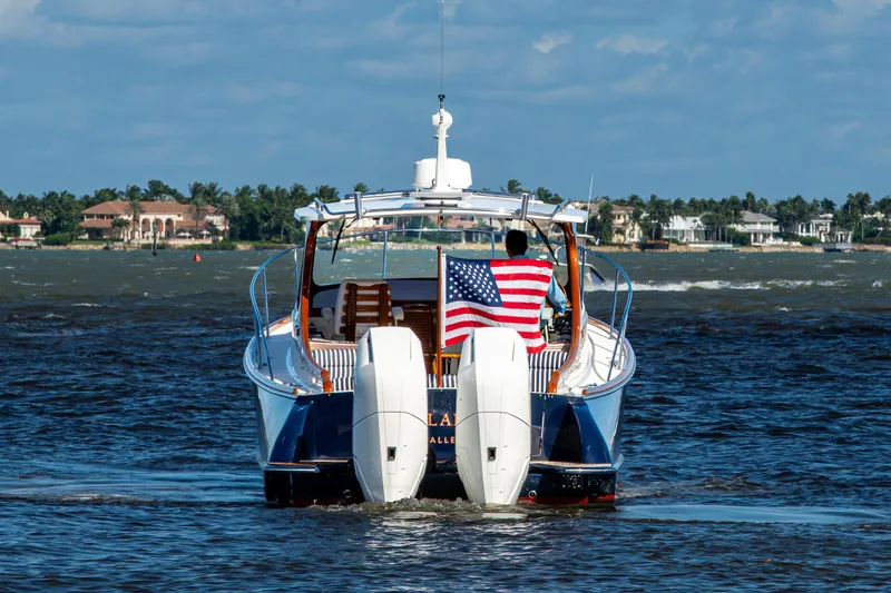 King's Landing Yacht Photos Pics 2024 Hinckley 35 boat cruising with American flag, coastal homes in background.
