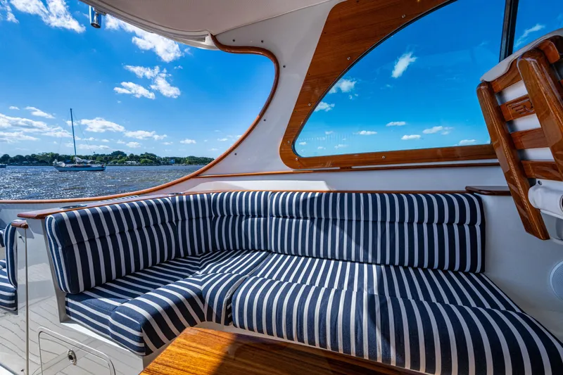 King's Landing Yacht Photos Pics 2024 Hinckley 35 yacht interior with striped seating, wooden accents, and scenic water view.
