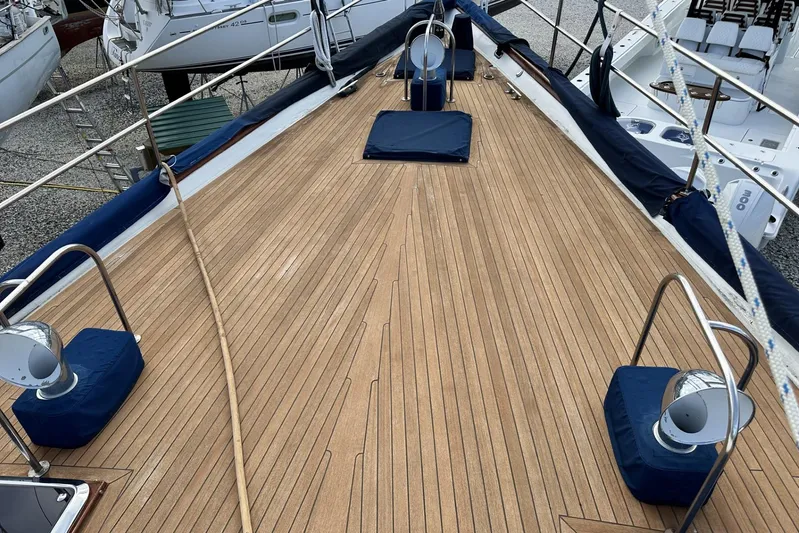 Wind Seeker 1 Yacht Photos Pics Teak deck of 1989 Windship 60 yacht, featuring polished metal fixtures and blue cushions.