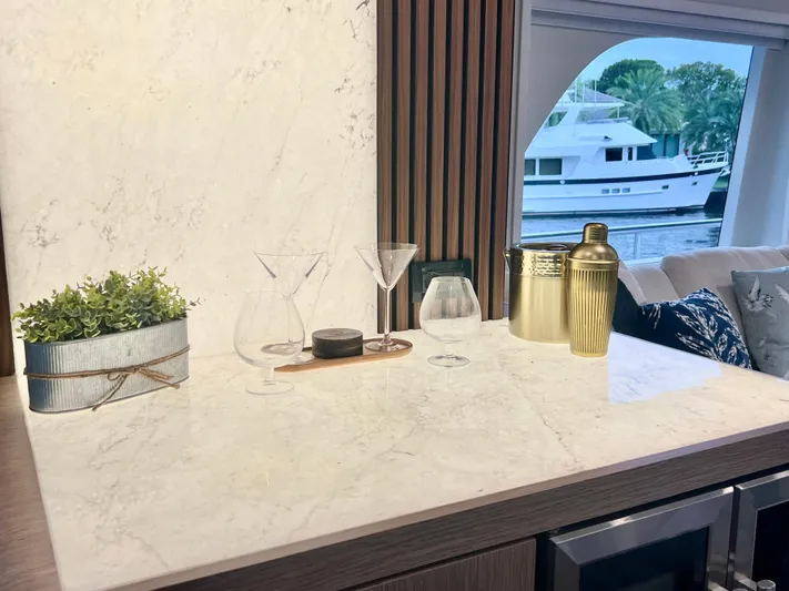 Panacea Yacht Photos Pics Luxurious yacht interior with marble countertop, glassware, and a view of a boat outside.