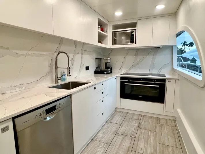 Panacea Yacht Photos Pics Modern yacht kitchen with sleek white cabinetry, stainless steel appliances, and marble backsplash.