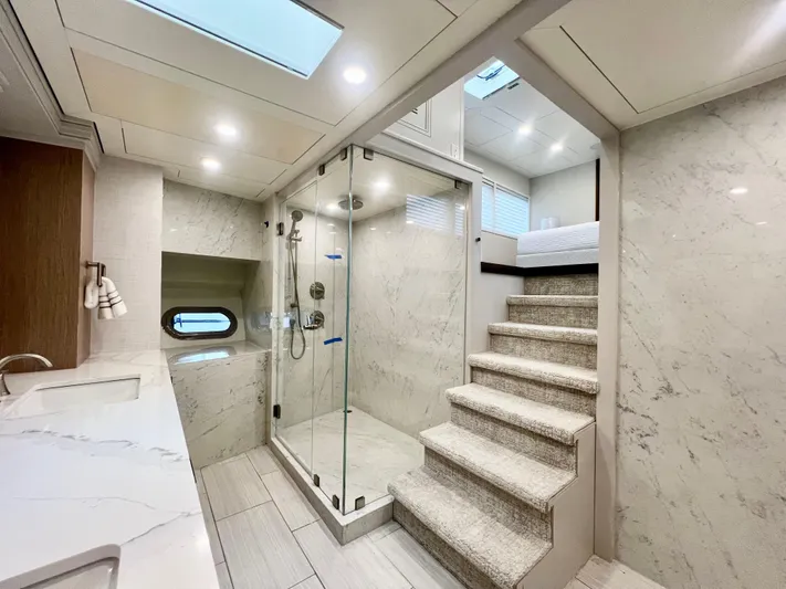 Panacea Yacht Photos Pics Luxurious yacht bathroom with marble shower, modern fixtures, and stairs leading to a bedroom.