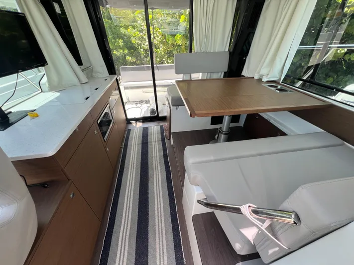 Yacht Photos Pics Interior of 2023 Jeanneau 1095 NC boat with modern seating, table, and kitchenette.