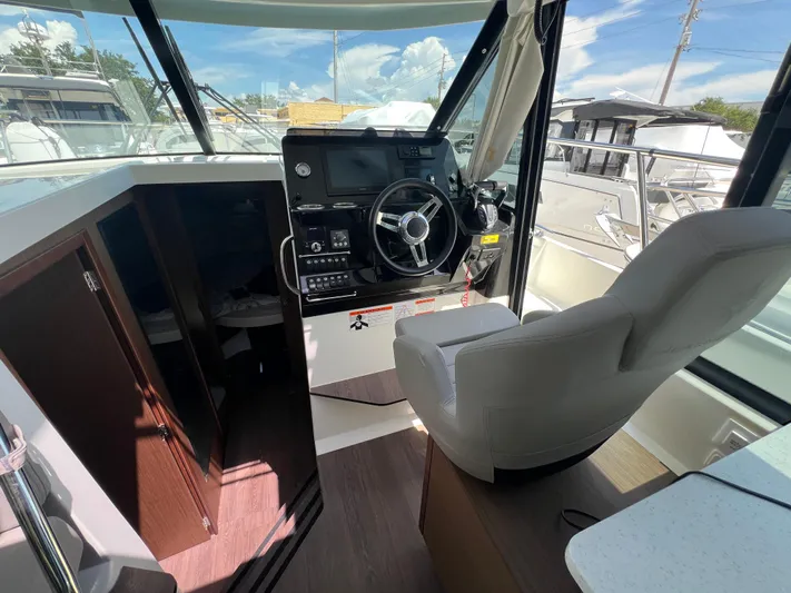  Yacht Photos Pics 2023 Jeanneau 1095 NC boat interior with steering wheel and captain's chair.