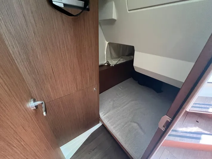  Yacht Photos Pics 2023 Jeanneau 1095 NC cabin interior with wooden door and cozy bed.
