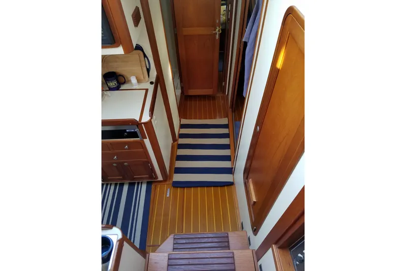 Escapade Yacht Photos Pics Interior of 1999 Legacy Yachts 40 Sedan with wooden flooring and striped rugs.