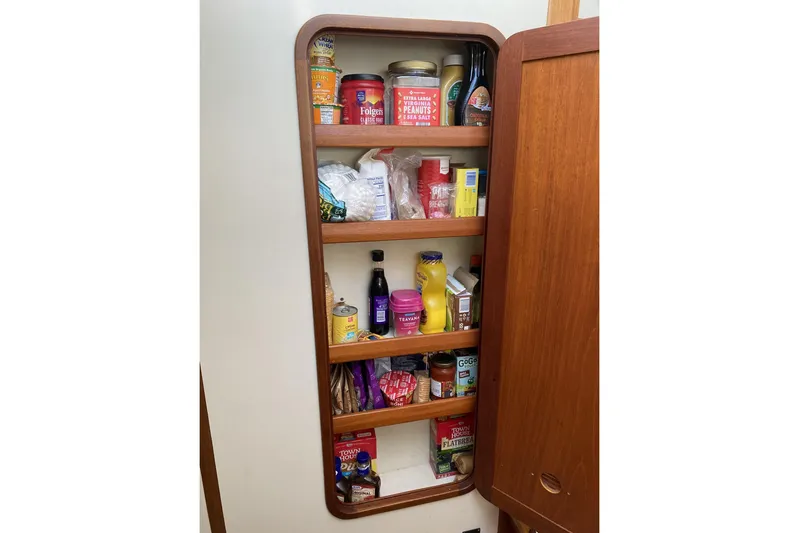 Escapade Yacht Photos Pics Pantry shelves on a 1999 Legacy Yachts 40 Sedan, stocked with various food items.
