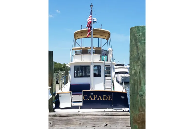 Escapade Yacht Photos Pics 1999 Legacy Yachts 40 Sedan docked, rear view with American flag, clear sky.