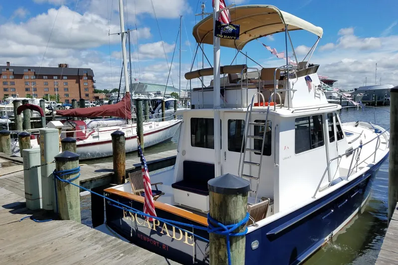Escapade Yacht Photos Pics 1999 Legacy Yachts 40 Sedan docked at marina, sunny day, blue sky, flags displayed.