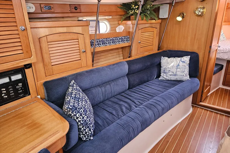 "juniper" Yacht Photos Pics Interior of 2006 Catalina 400 MkII sailboat with blue cushioned seating and wooden cabinetry.