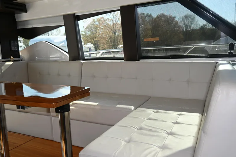 Present Tense Yacht Photos Pics Luxurious interior of 2017 Tiara 44 Coupe with white leather seating and wooden table.
