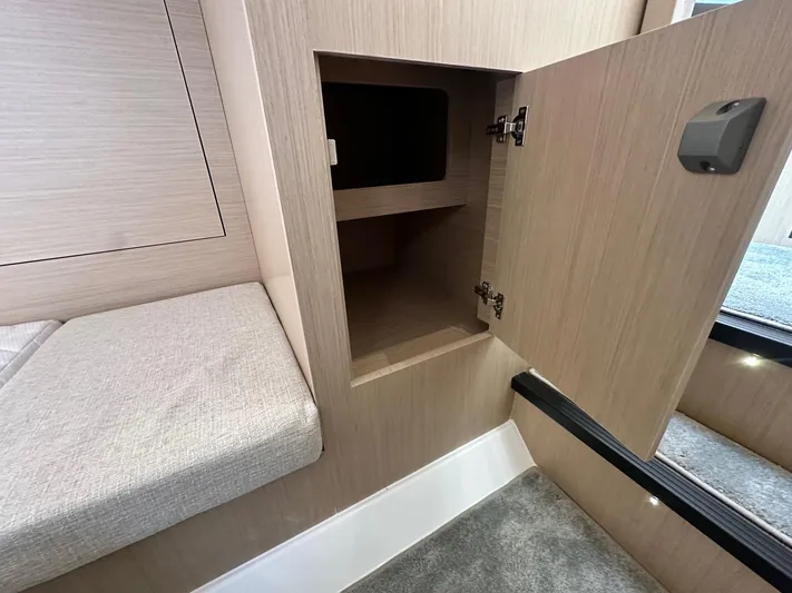  Yacht Photos Pics 2025 Jeanneau DB/37 OB interior with open wooden cabinet and cushioned seating.