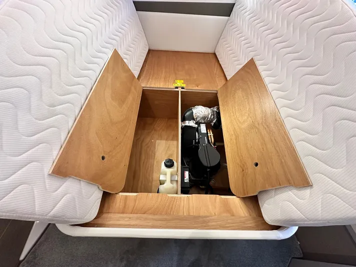  Yacht Photos Pics Under-seat storage compartment in 2025 Jeanneau DB/37 OB boat, featuring wooden panels and equipment.