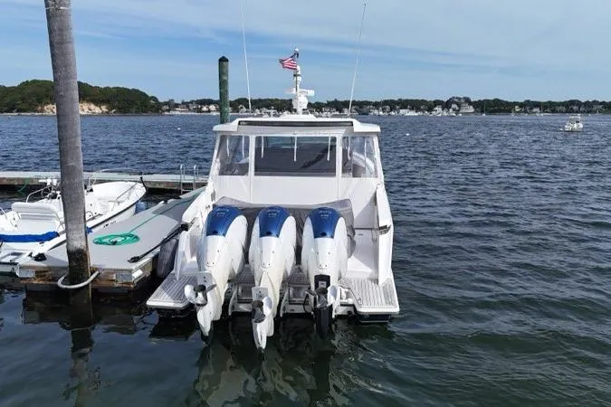Carry On Yacht Photos Pics 2021 Tiara Sport 43 LS boat docked with triple outboard engines on a calm lake.