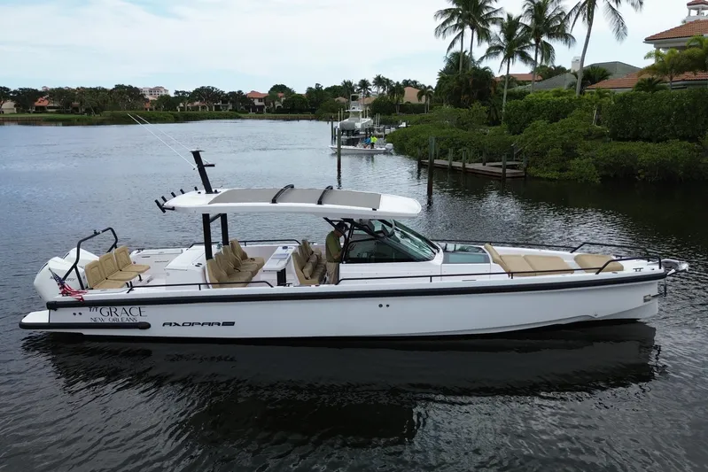 T/t Grace Yacht Photos Pics 2021 Axopar 37 Sun Top boat on calm water, surrounded by lush greenery and palm trees.