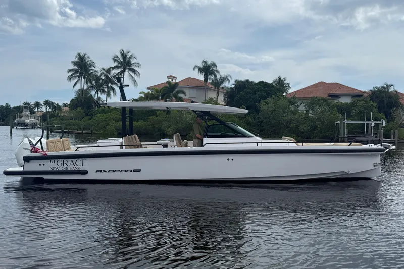 T/t Grace Yacht Photos Pics 2021 Axopar 37 Sun Top boat on calm water, surrounded by lush greenery and houses.