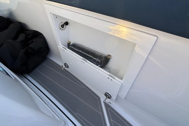  Yacht Photos Pics 2026 Monterey Elite 30 OB boat storage compartment with hose and black bag.