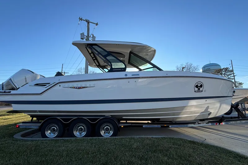  Yacht Photos Pics 2026 Monterey Elite 30 OB boat on trailer, side view, clear sky background.