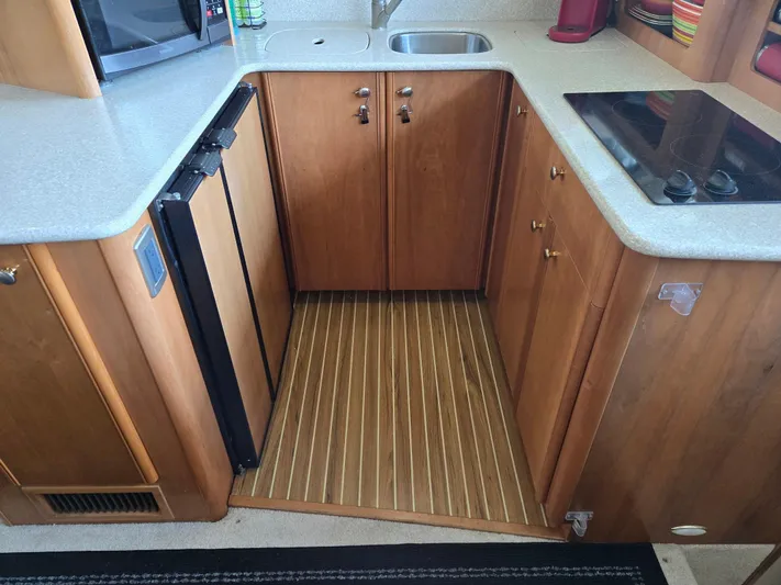 Mad Mary Yacht Photos Pics Compact kitchen area in a 2004 Meridian 381 Sedan yacht, featuring wood cabinetry and modern appliances.