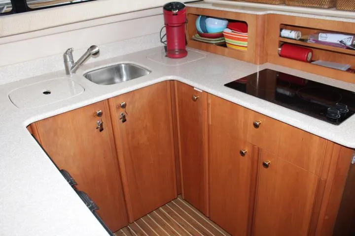 Mad Mary Yacht Photos Pics Compact kitchen in 2004 Meridian 381 Sedan with sink, stove, and wooden cabinets.