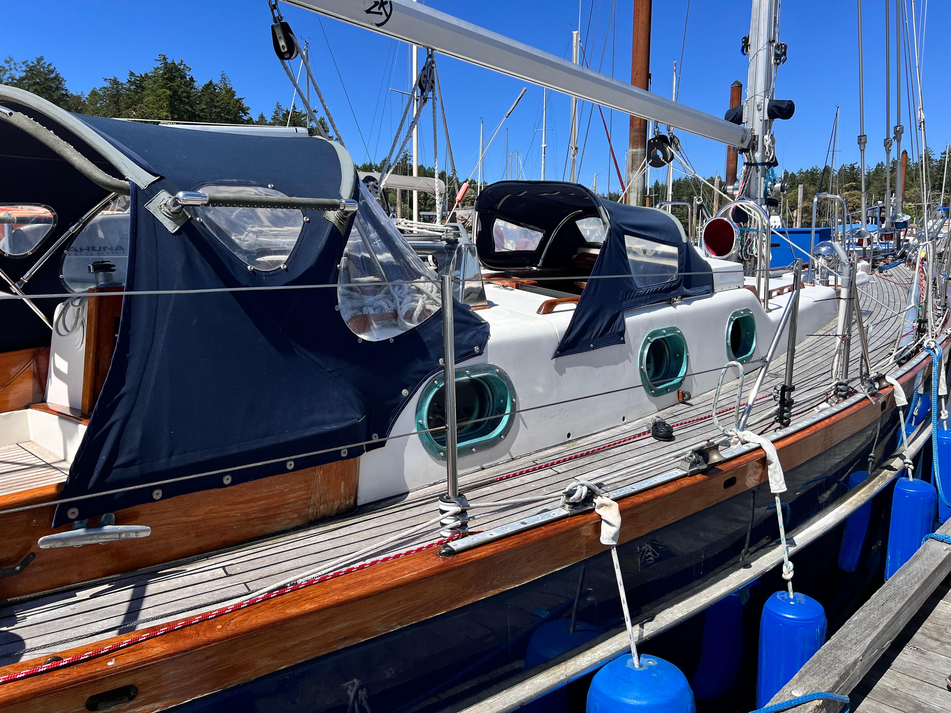 Sailboat docked in marina, Reliance 45 model, 1987, with blue canopy and wooden accents.