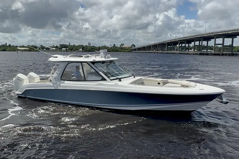  Yacht Photos Pics 2023 Boston Whaler 380 Realm boat cruising on a river under a cloudy sky.