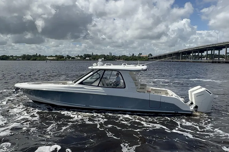  Yacht Photos Pics 2023 Boston Whaler 380 Realm boat cruising on a river under cloudy skies.